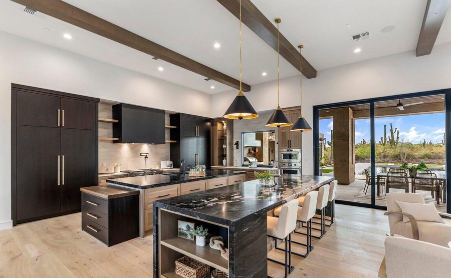Kitchen island with pendant lighting and saguaro views through a glass wall